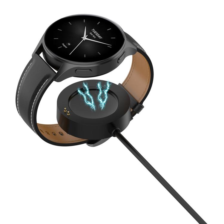 Black smartwatch attached to its magnetic charging pad and cable