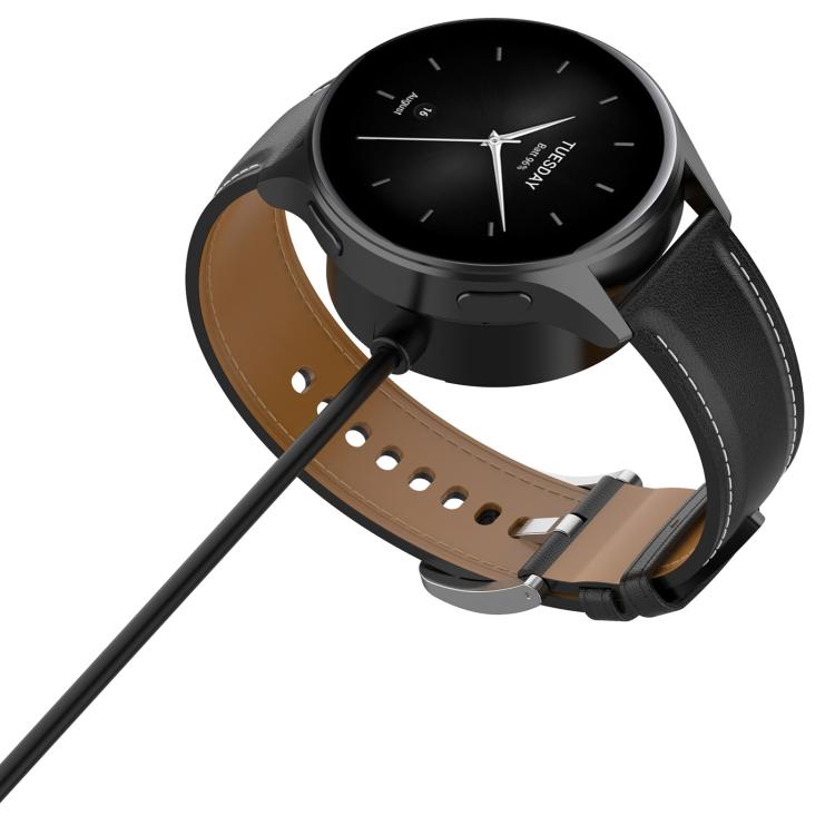 Black smartwatch connected to its charging cable, showing the watch face and strap