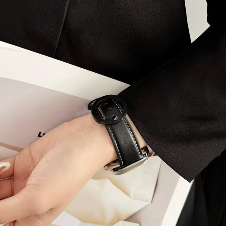 Black leather watch band with white stitching and a round buckle, worn on a wrist