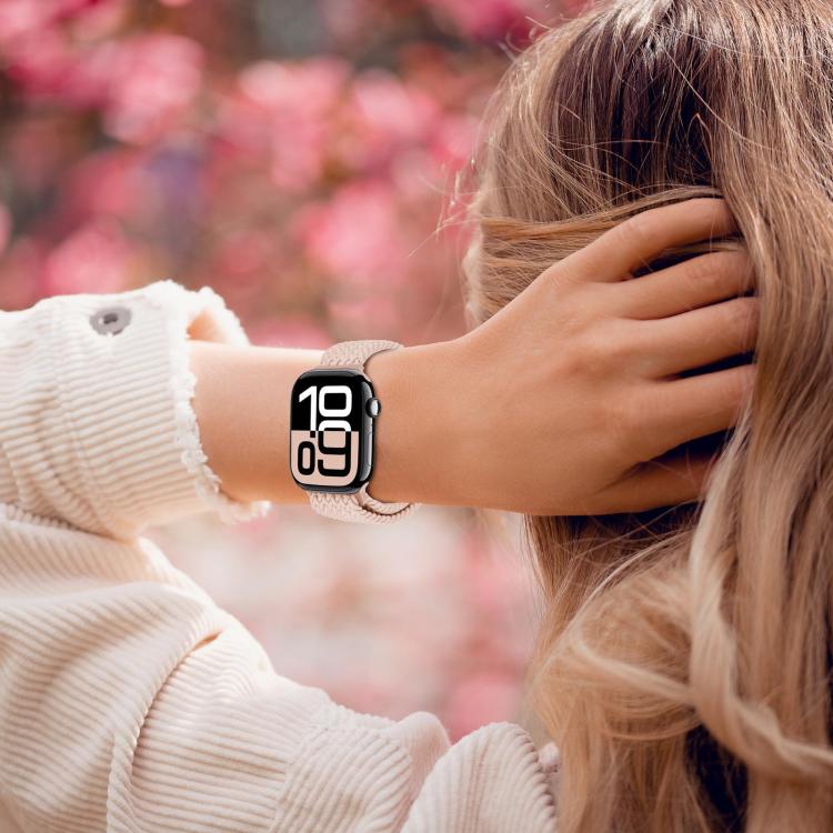 Light pink woven watch band worn on a wrist with an Apple Watch