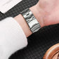 Silver linked titanium alloy watch band with folding buckle, worn around a wrist
