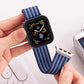 Blue striped braided nylon watch band attached to a smartwatch, shown flexed for adjustment