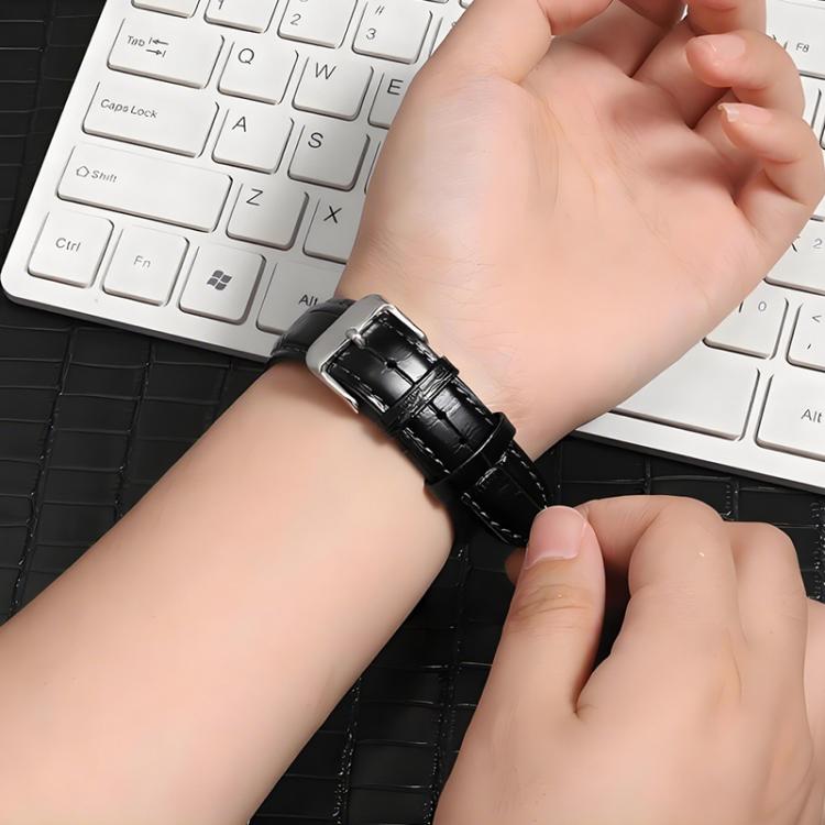 Black leather watch band worn on a wrist, showing the silver pin buckle.