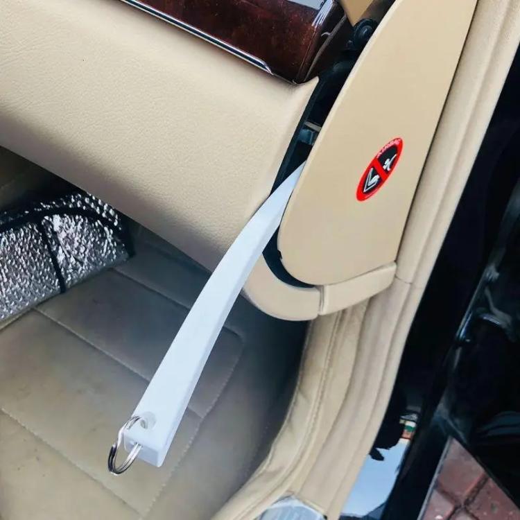 Light gray trim removal tool with loop ring prying open a car interior panel gap