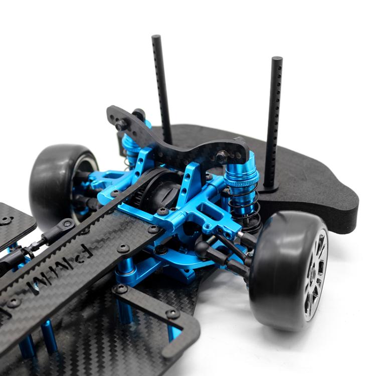 Angled view 1:10 RC 4WD chassis with blue suspension arms, black belt-drive parts, and tires