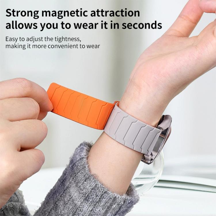 Orange and light gray magnetic silicone watch band being fastened around a wrist