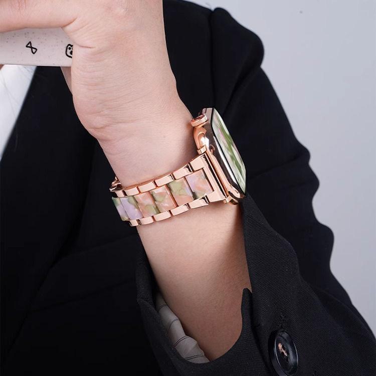 Close-up of a rose gold watch band with pale iridescent resin links
