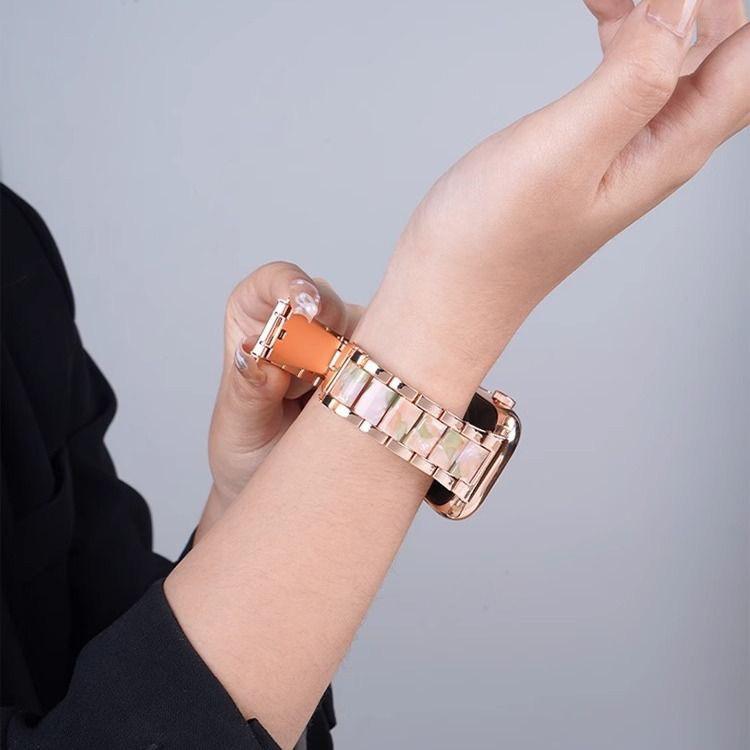 Rose gold metal and resin watch band worn on a wrist