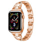 Rose gold X-shaped metal Apple Watch band with crystal accents, shown attached to a watch