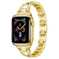 Gold X-shaped metal Apple Watch band with crystal accents, shown attached to a watch