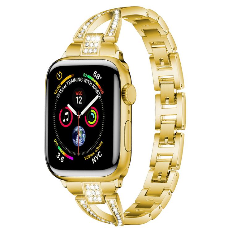 Gold X-shaped metal Apple Watch band with crystal accents, shown attached to a watch