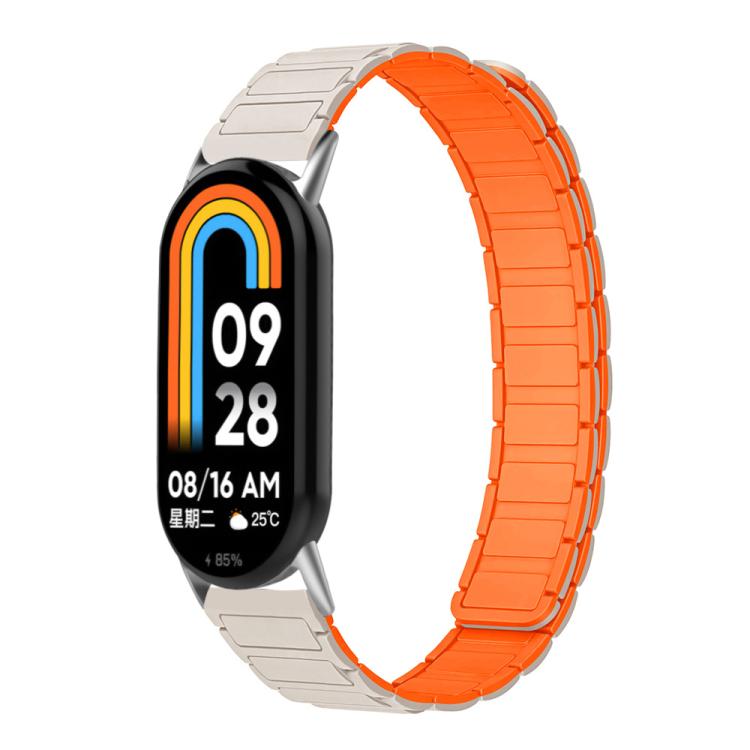 Two-tone silicone watch band in starlight and bright orange, shown on a smart band.
