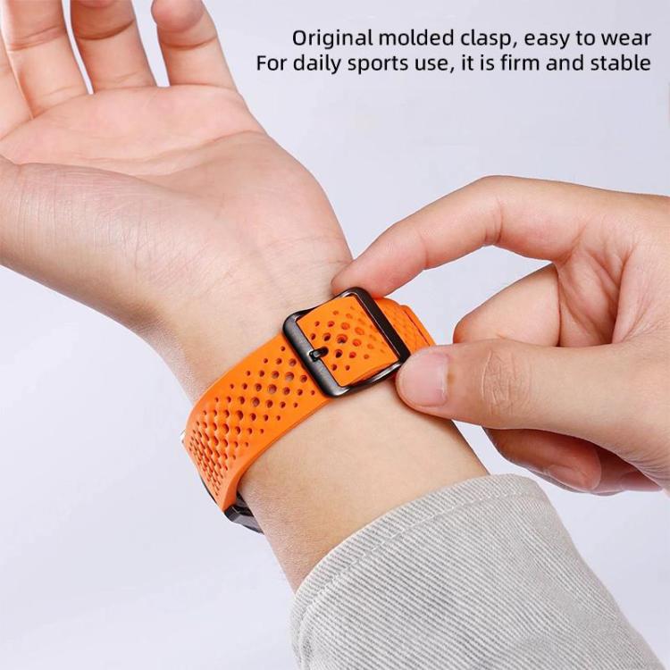 Orange perforated silicone watch band fastened around a wrist with a black buckle