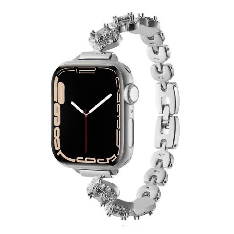 Silver metal Apple Watch band with crystal four-leaf clover links, shown attached to a watch