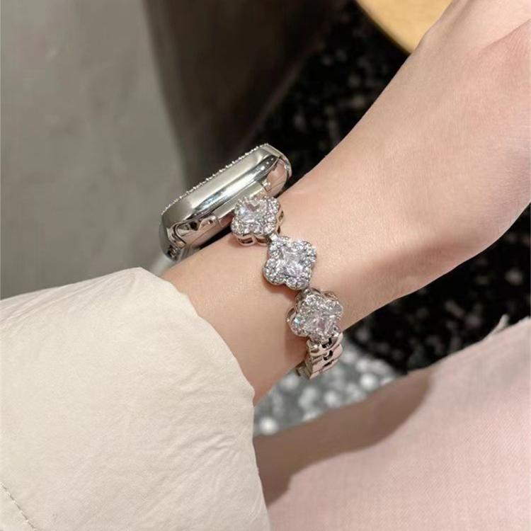 Silver metal Apple Watch band with crystal clover links worn on the wrist