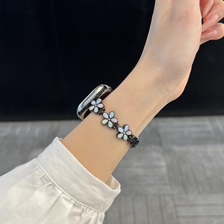 Silver flower-link Apple Watch band worn on a wrist.