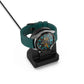 Black watch charging stand holding a watch with teal strap; cable connected