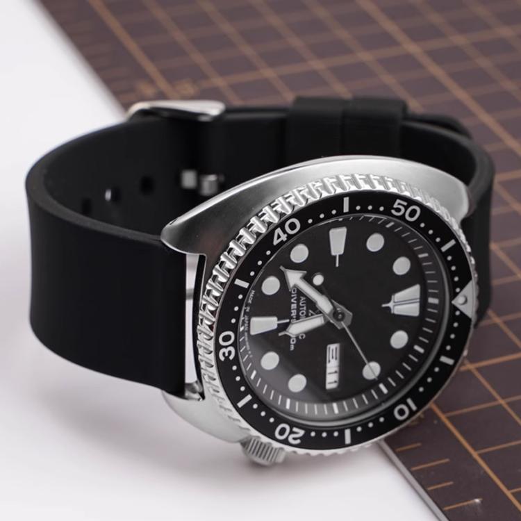 Black silicone watch band with a silver pin buckle, shown fitted to a silver watch