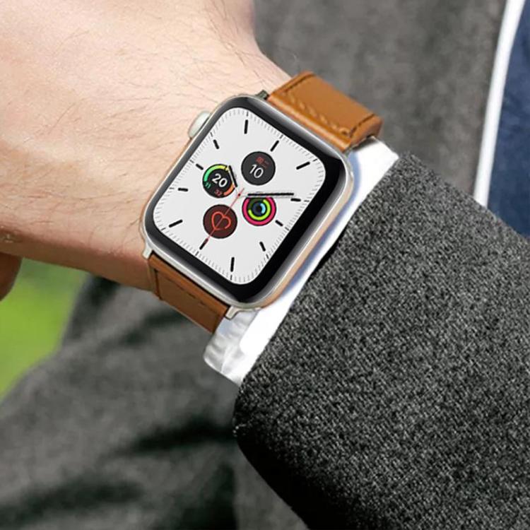 Tan leather watch band fastened around a wrist with a silver smartwatch.