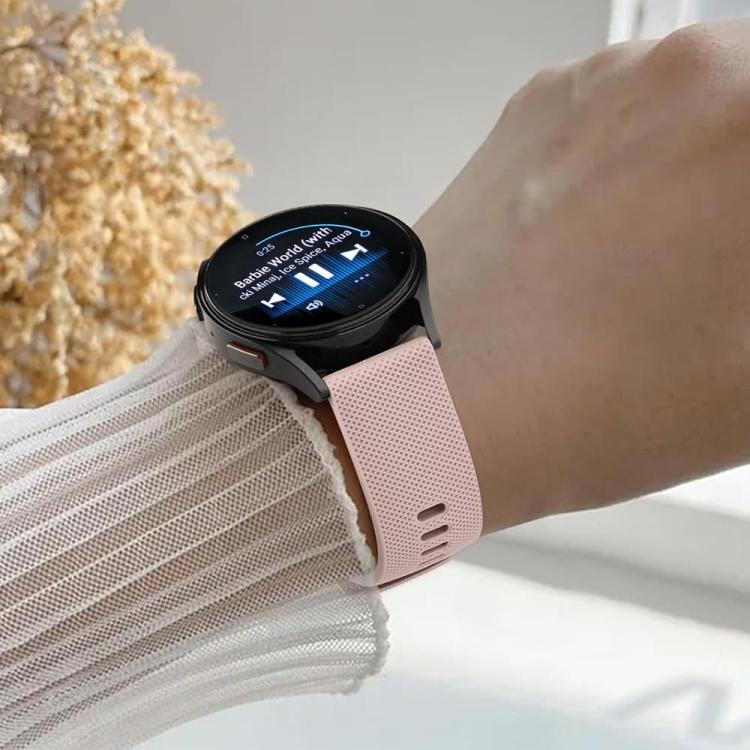 Pink perforated silicone watch band attached to a smartwatch on a wrist