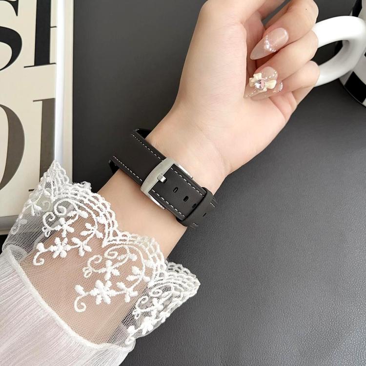 Black vegan leather watch band with white stitching and silver buckle, worn on wrist.