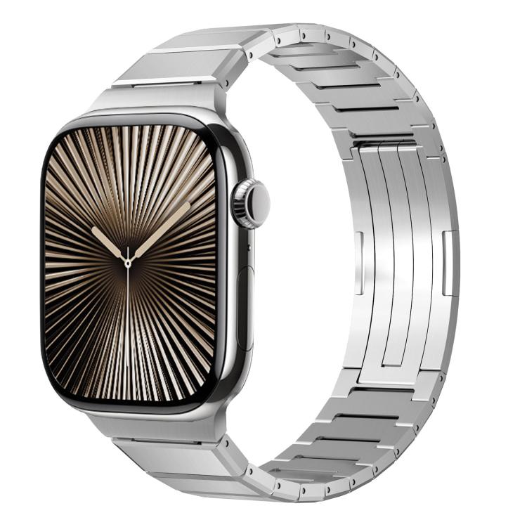 Silver-tone metal Apple Watch band with linked bracelet and folding clasp, shown attached to watch.