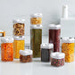 Food storage container set of multiple clear jars with white lids, filled with assorted dried foods