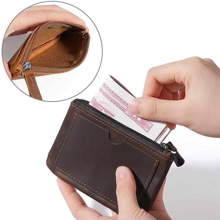 Dark leather coin purse wallet held in hand, zipper opening with card inside