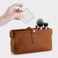 Tan leather cosmetic clutch bag with snap closure, front seam panel, and open top