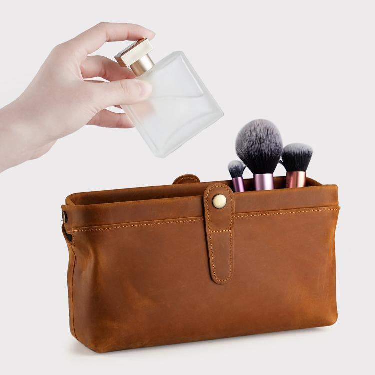 Tan leather cosmetic clutch bag with snap closure, front seam panel, and open top