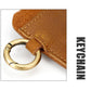 Close-up of brown leather strap with brass ring hardware and stitched edge