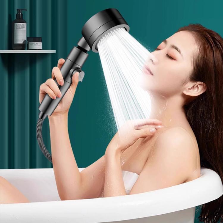 Handheld shower head in use, releasing a wide mist spray toward a person