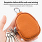 Orange pebble-grain mini leather coin pouch with metal zipper and attached key ring keys