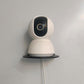 Wall-mounted rack supporting a small white security camera on a black base