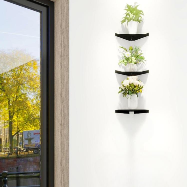 Wall-mounted triangular black corner shelf holding potted plants