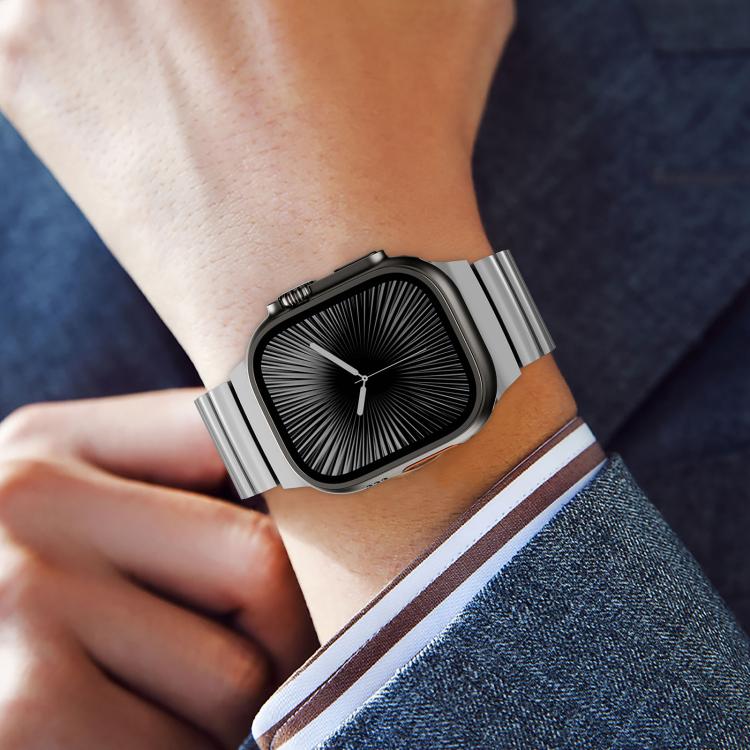 Silver titanium Apple Watch band with a magnetic clasp, worn with a dark watch face.