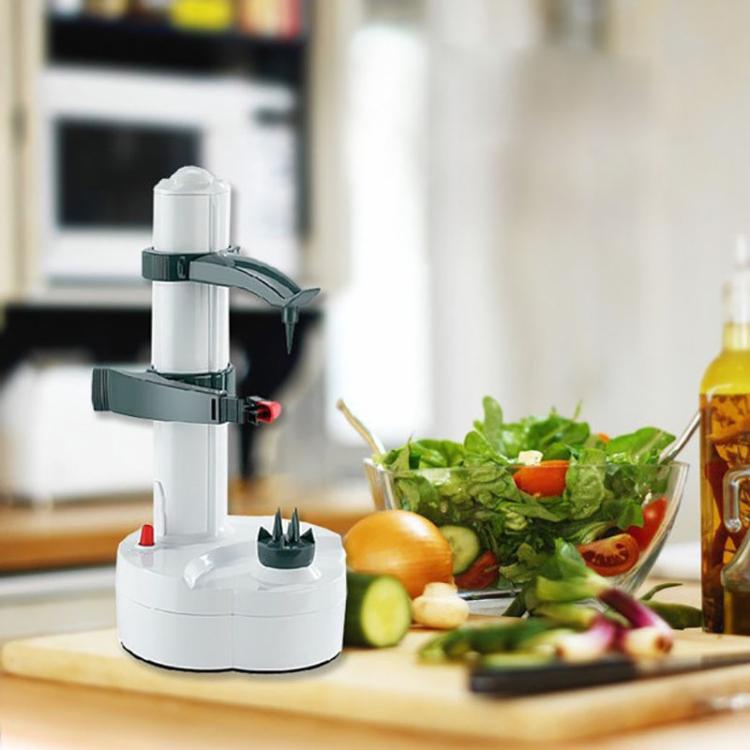 White electric vegetable peeler on counter with leafy greens and fruit