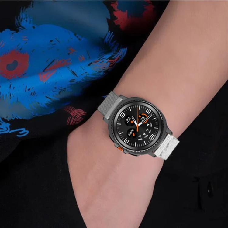 Silver Milanese watch band worn on a wrist with a black smartwatch