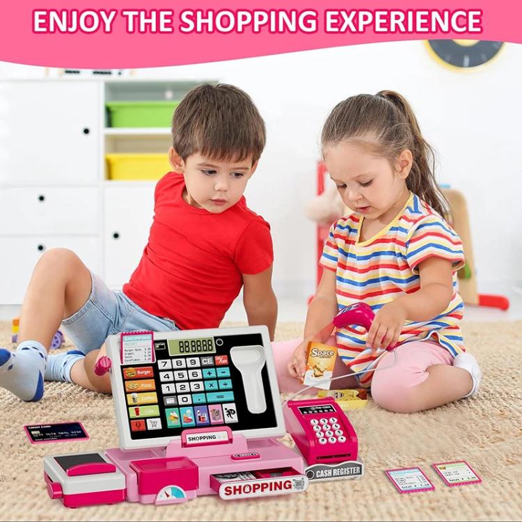 Pink shopping cash register playset on floor table while children play