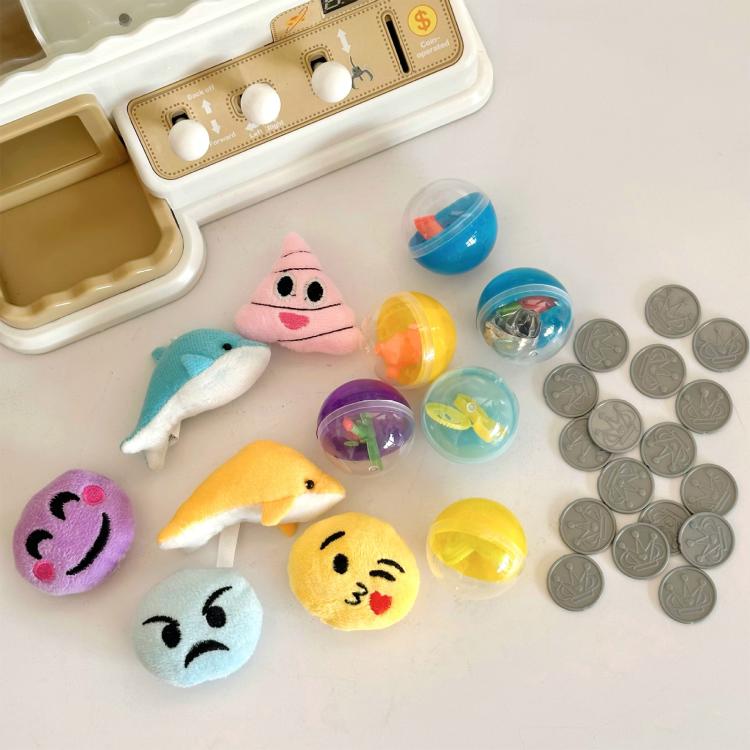 Mini claw game machine prize area with plush toys, capsule balls, and coins