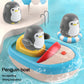 Children's bath toy penguin boat with two penguins and a red water sprayer on the dock