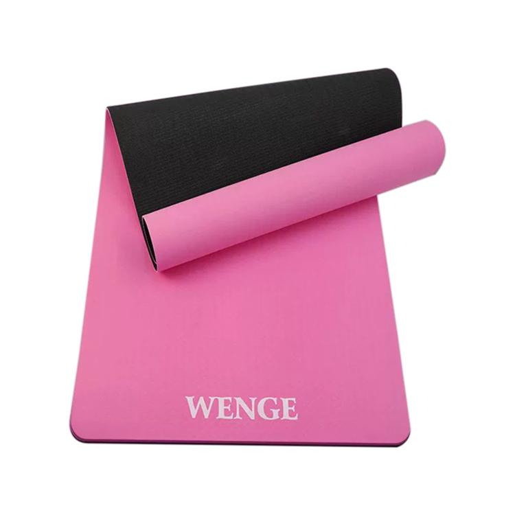 Peach pink and black non-slip yoga mat rolled up with textured grip surface