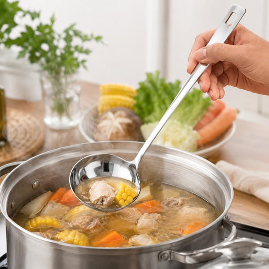 Stainless steel soup ladle with long handle, held above a pot of soup and vegetables.