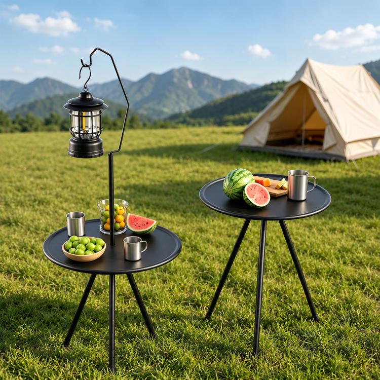 Pair of round black camping tables with legs, holding drinks and fruit