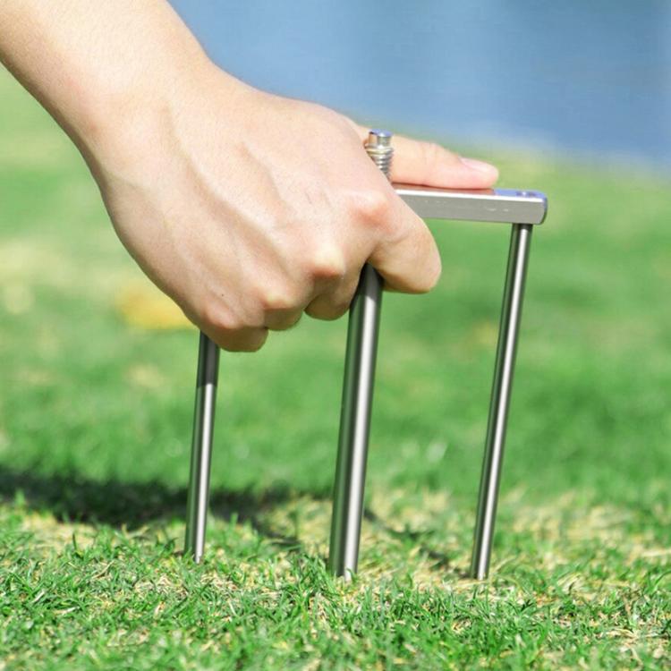 Hand pressing chrome umbrella ground stake prongs into the lawn for stability
