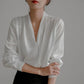 White satin V-neck blouse with long sleeves and gathered neckline placket