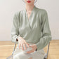 Light green satin V-neck blouse with long sleeves, front view with pleated texture