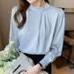 Light blue mock neck blouse with pearl button and pleated front, long sleeves