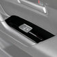 Black window lift switch trim panel with silver button outlines on car door