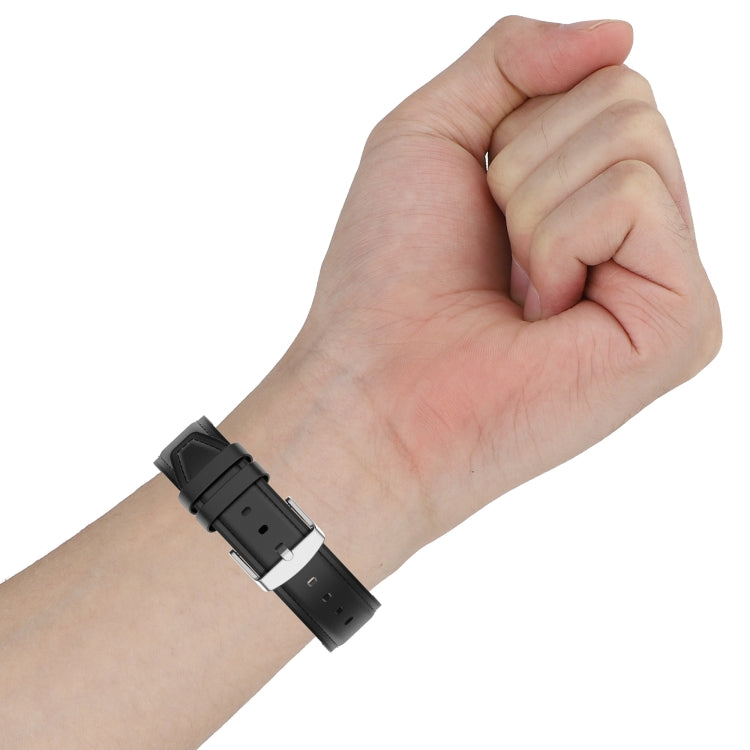 Black silicone watch strap on wrist with metal buckle and adjustment holes